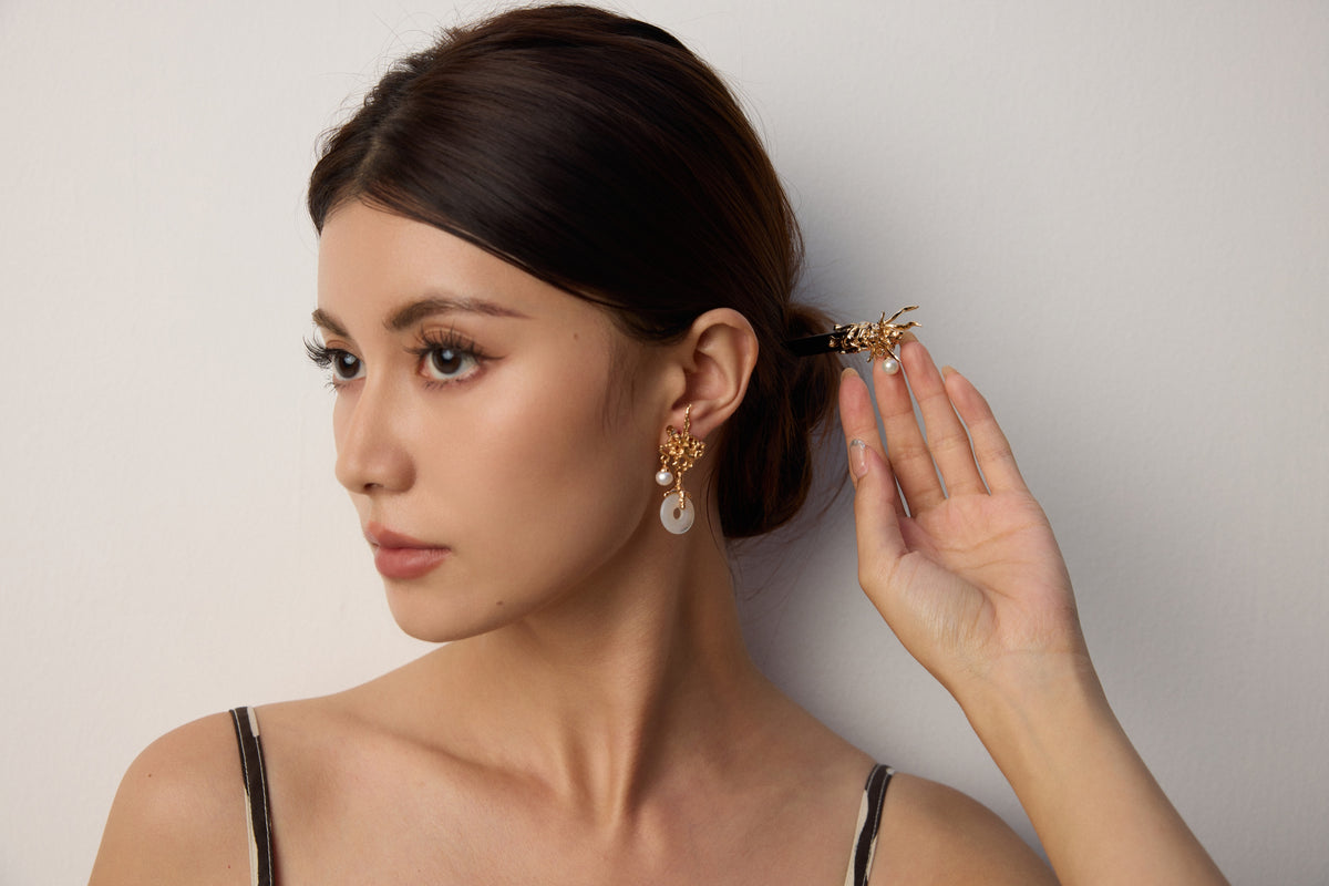 Kairos model wearing pearl and gold jewelry in a softly lit studio