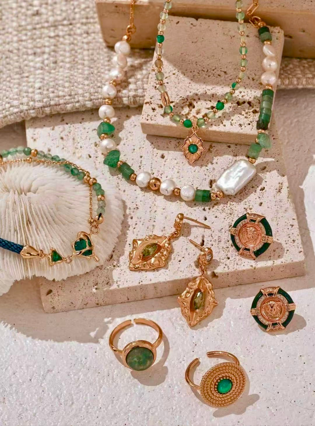 Kairos pearl and green gemstone jewelry arranged on stone